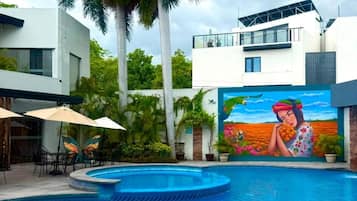 Una piscina con un mural, palmeras y edificios modernos.