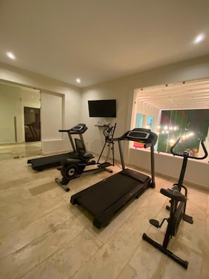 A home gym with a treadmill, elliptical, and stationary bike.