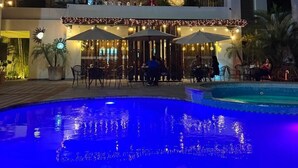 A poolside area with a dining setup and a building with a flat roof. - Grann Hotel (Ciudad Valles)