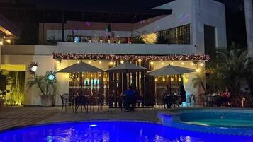 Zona de piscina con mobiliario para comer y un edificio de techo plano.