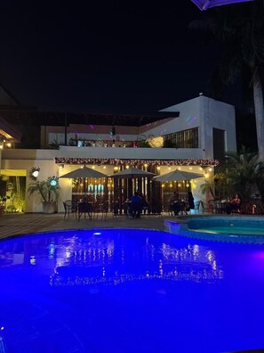 A poolside area with a dining setup and a building with a flat roof. - Grann Hotel (Ciudad Valles)