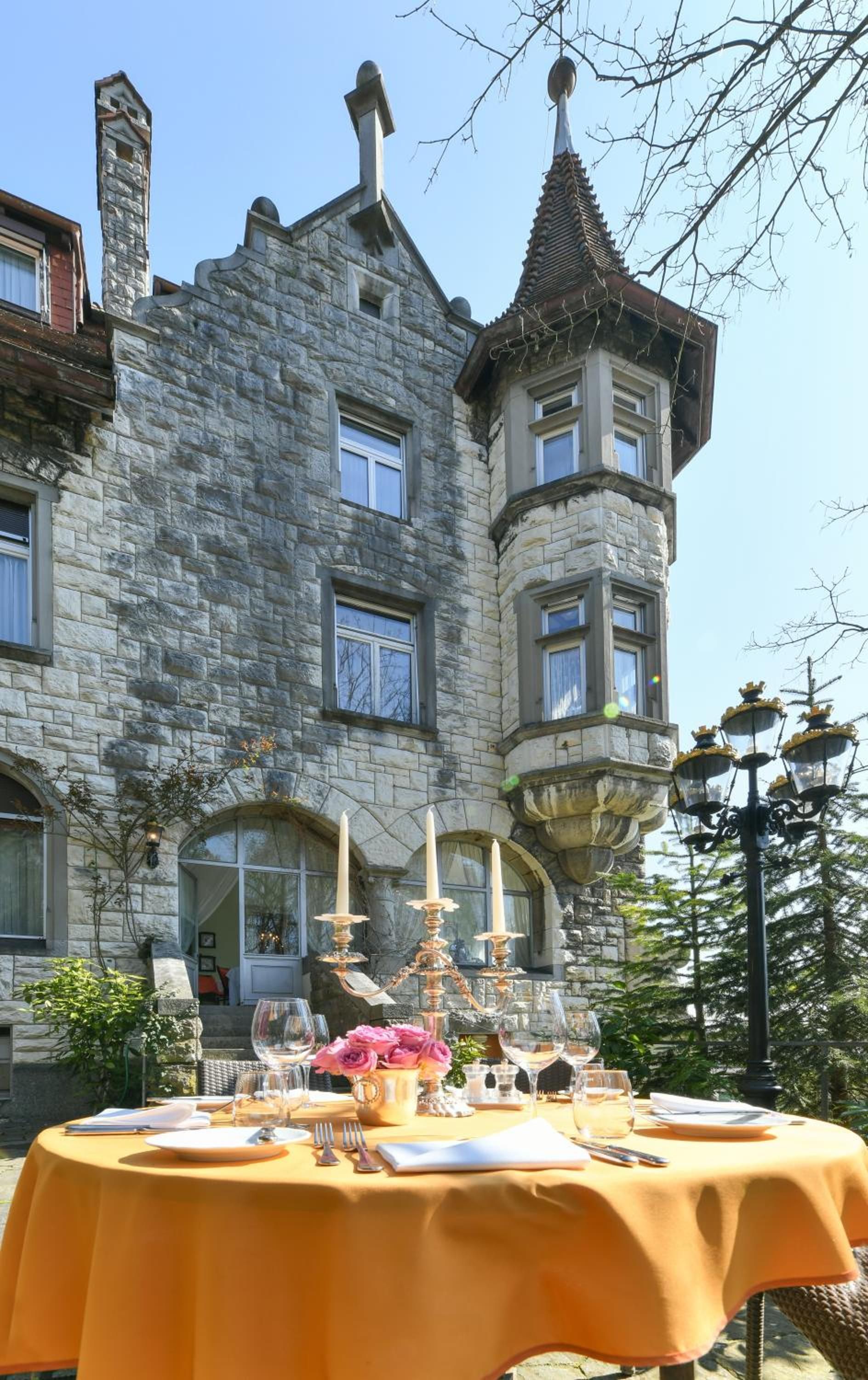 Ein Steinhaus mit einem Türmchen und einem Tisch, gedeckt für ein Essen im Freien.