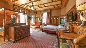 A traditional room with a wooden bed, a dresser, a desk, and a chandelier.