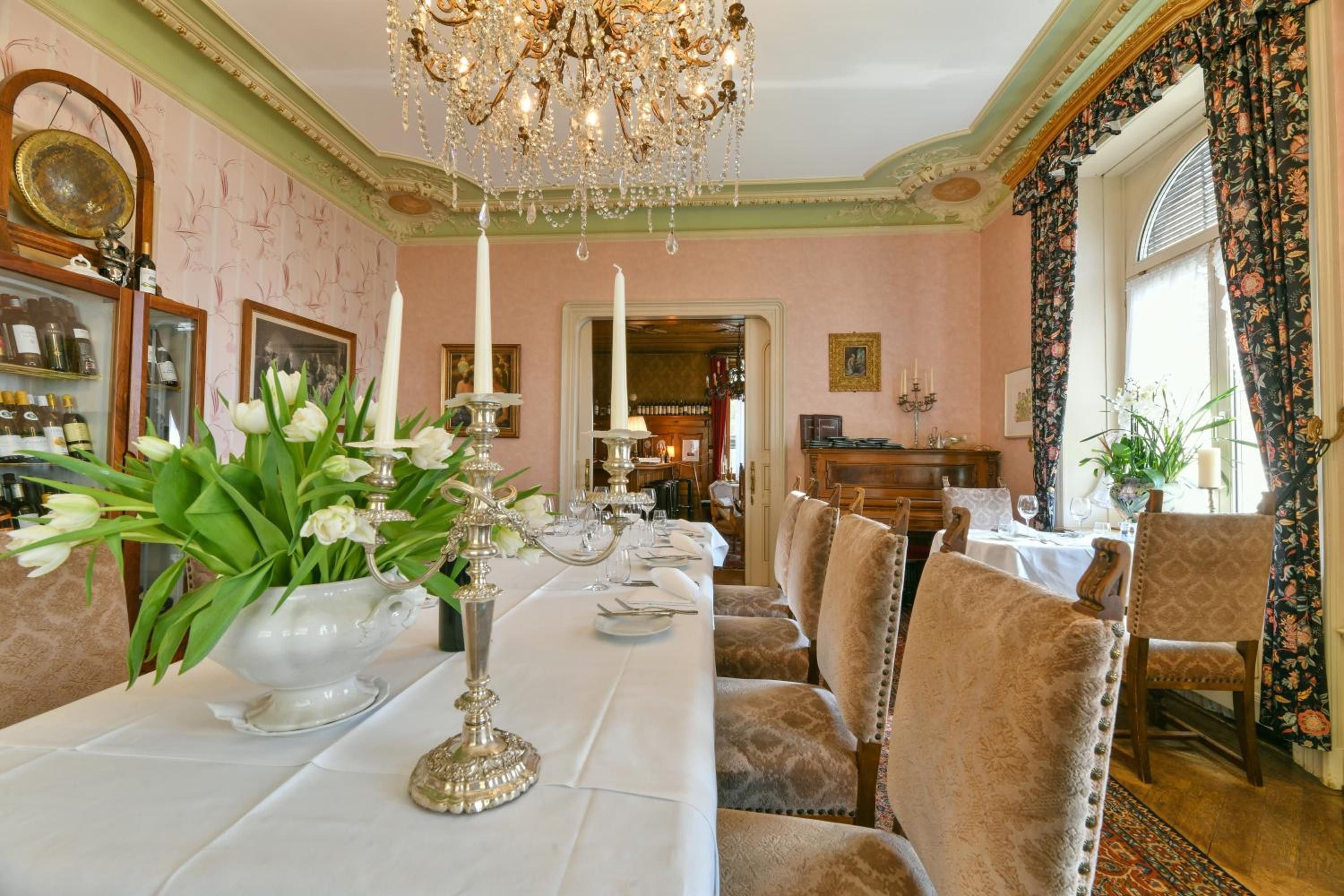 Ein formeller Speisesaal mit einem langen Tisch, gedeckt für eine Mahlzeit, umgeben von gepolsterten Stühlen.