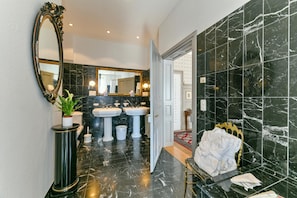 Une salle de bain avec deux lavabos, un grand miroir et un sol en marbre.