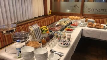 Ein reichhaltiges Buffet mit verschiedenen Speisen und Besteck, darunter Obst, Gebäck und Soßen.