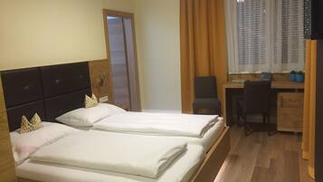 Ein Hotelzimmer mit zwei Betten, einem Schreibtisch, einem Stuhl und einem Fernseher.