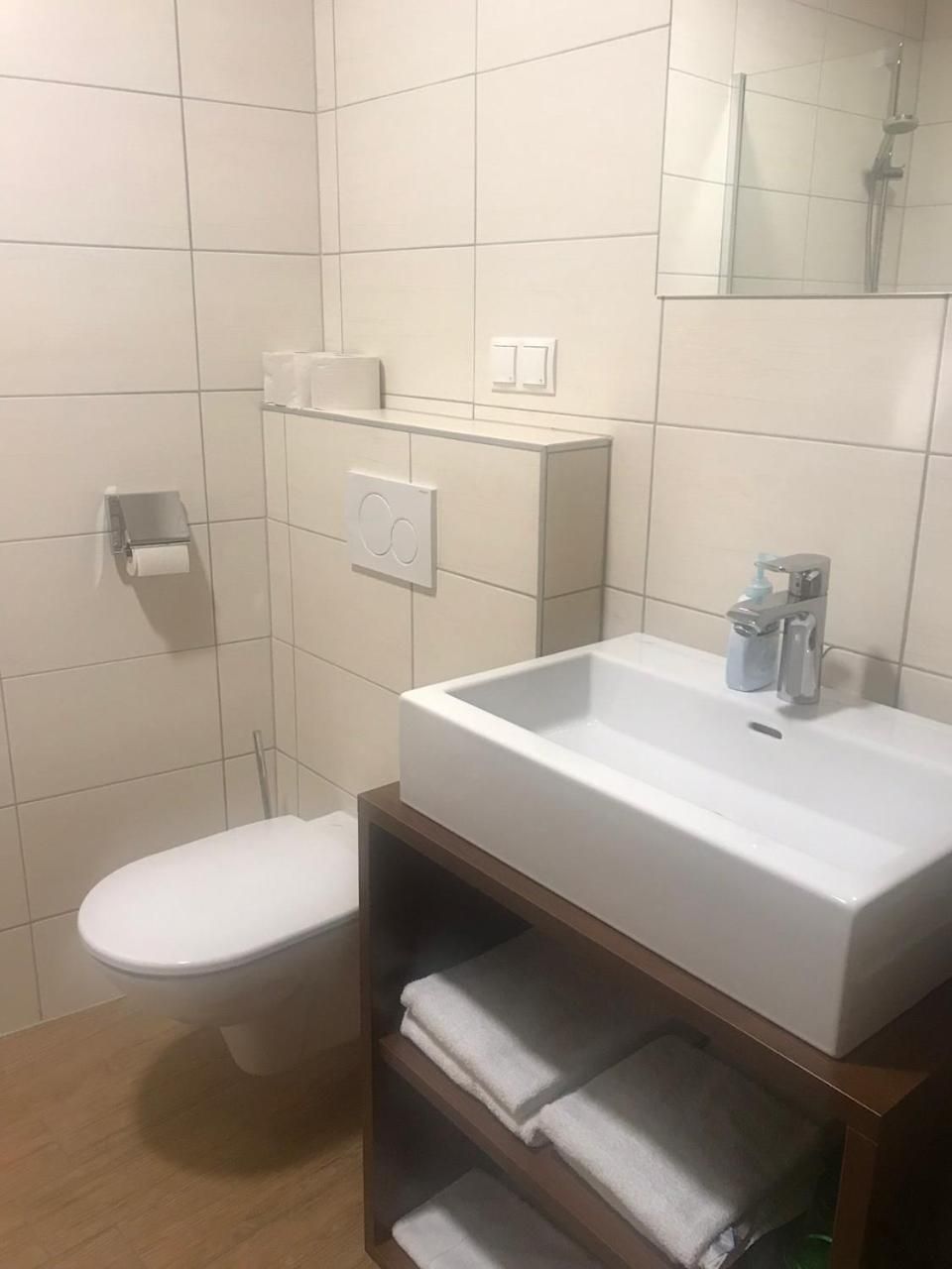 Ein Badezimmer mit einem weißen Waschbecken, einer Toilette und einem Handtuchregal.