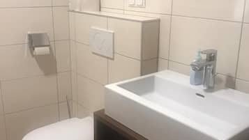 Ein Badezimmer mit einem weißen Waschbecken, einer Toilette und einem Handtuchregal.