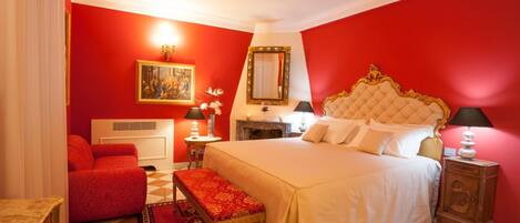 A hotel room with a large bed, a red wall, and a checkered floor.