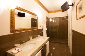 A bathroom with two sinks, a large mirror, a shower, and a flat-screen TV mounted on the wall. - Martins Residence De Luxe (Ravenna)