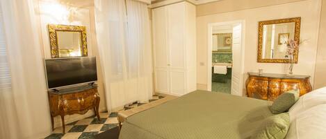 A hotel room with a bed, a television, a dresser, and a bathroom visible through an open door.