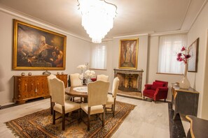 A dining room with a round table, chairs, a chandelier, a fireplace, and artwork on the walls. - Martins Residence De Luxe (Ravenna)