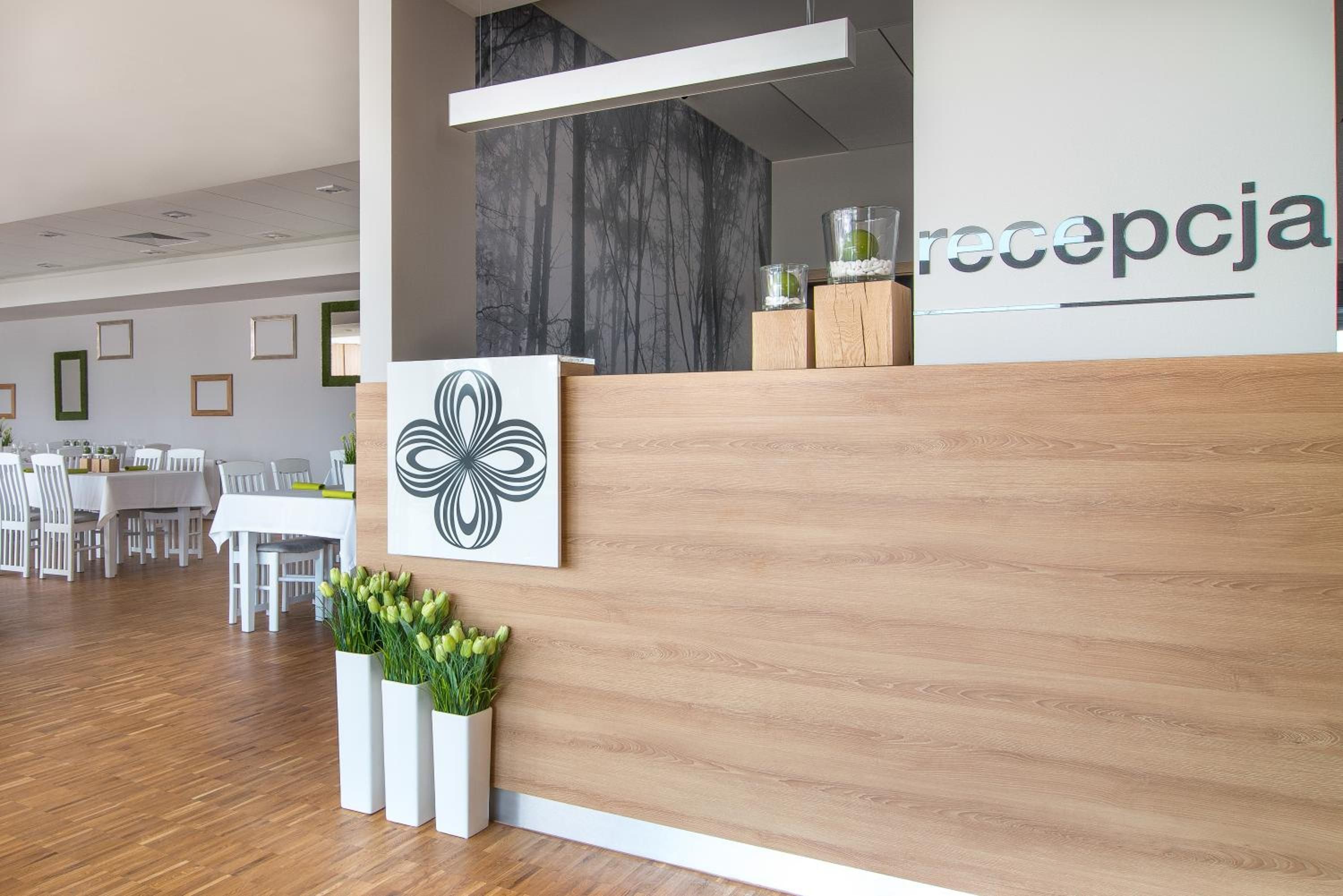 A reception area with a wooden reception desk, a wall-mounted artwork, and a reception sign.