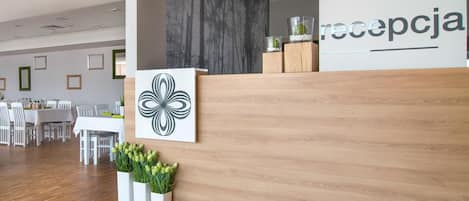 A reception area with a wooden reception desk, a wall-mounted artwork, and a reception sign.