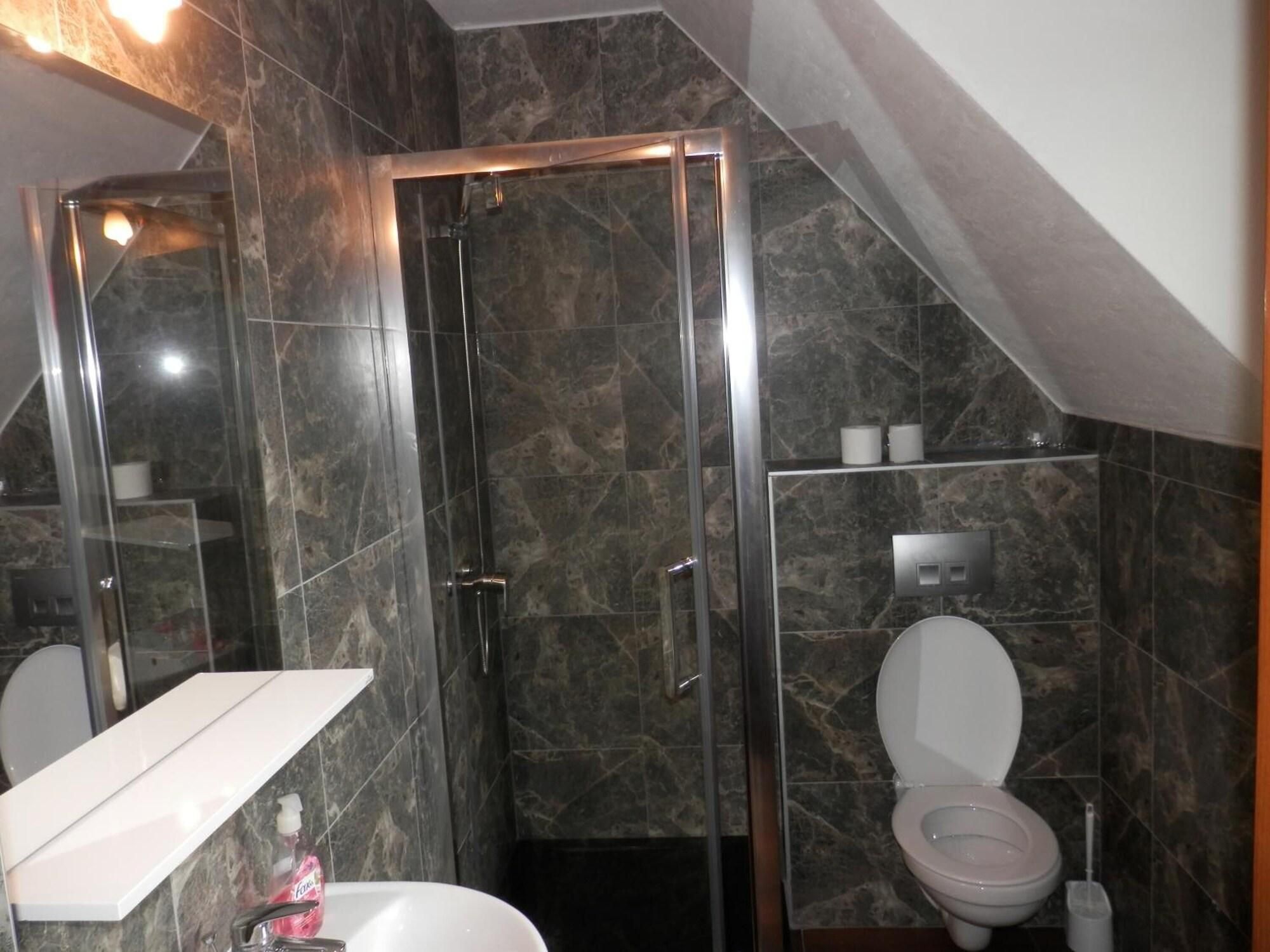 Un baño con cabina de ducha de vidrio, un lavabo blanco y un inodoro.