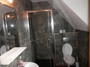 Een badkamer met een douchecabine van glas, een wit wastafelmeubel en een toilet.