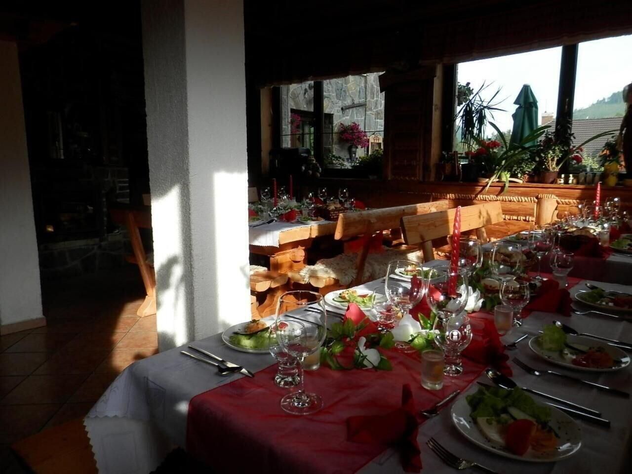 A dining area with tables set for a meal, featuring a view of the outdoors through large windows.
