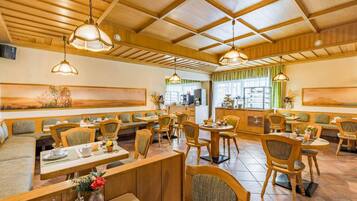 A restaurant with wooden furniture, multiple seating areas, and pendant lighting.