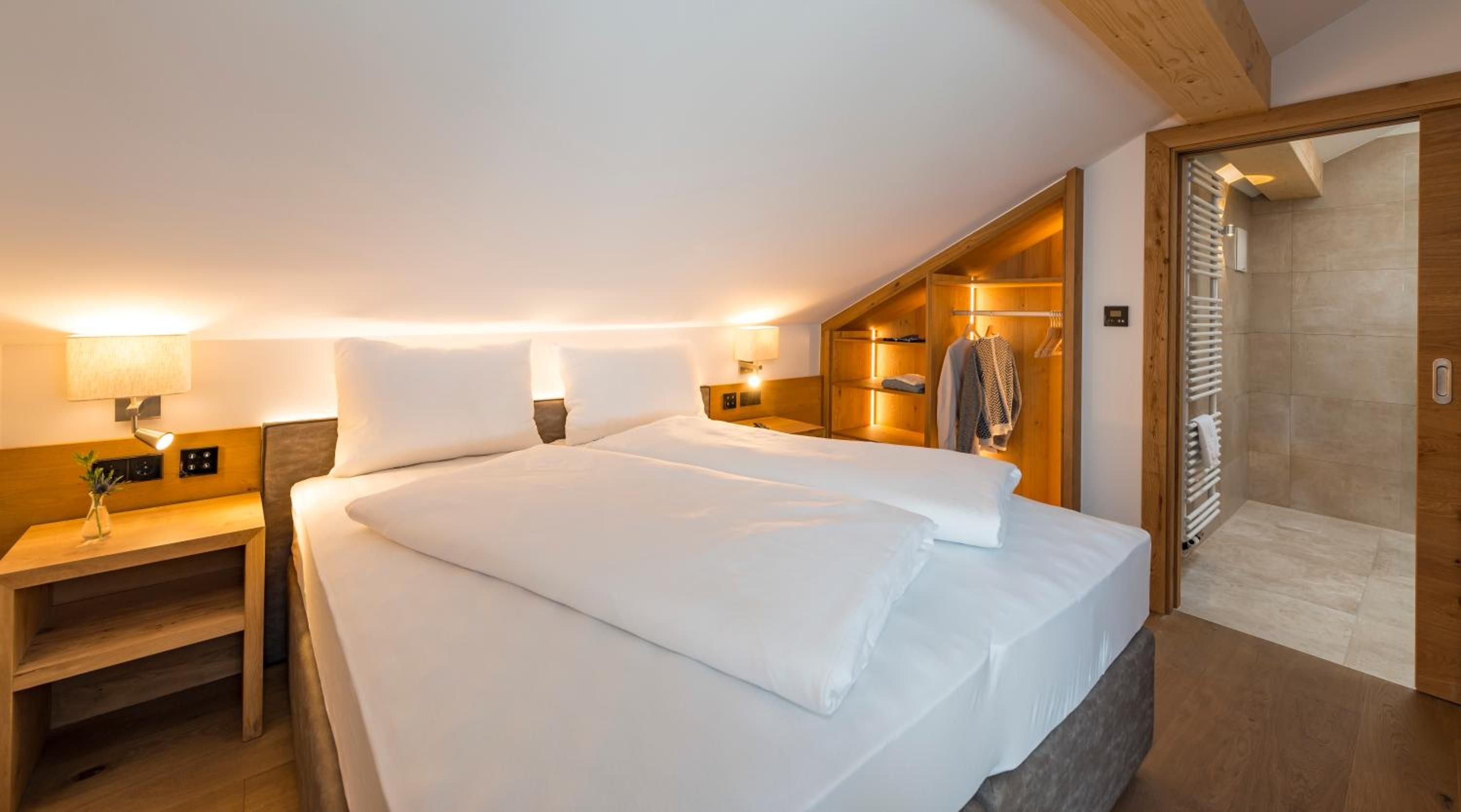 Une chambre d’hôtel avec un grand lit, des tables de chevet, une armoire intégrée et un espace douche.