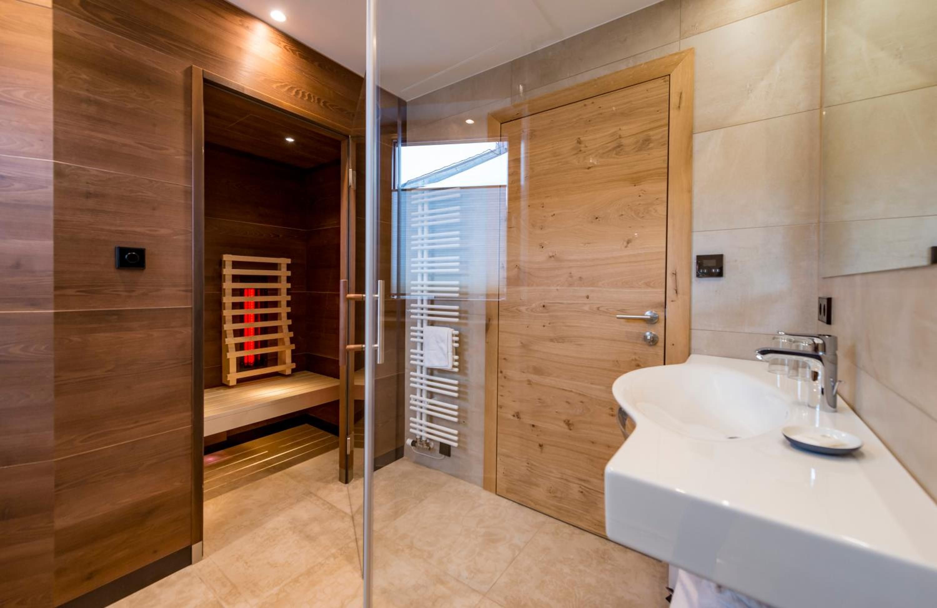 Une salle de bain moderne avec un meuble-lavabo en bois, une cabine de douche en verre et un sauna intégré.