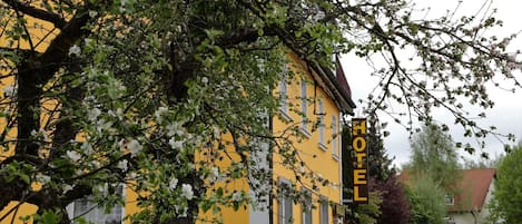 Un edificio amarillo con un letrero que dice 'HOTEL' y un árbol en la parte delantera.
