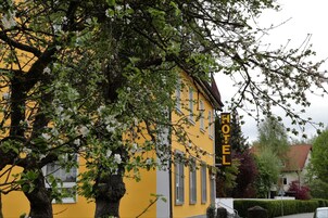 Un edificio amarillo con un letrero que dice 'HOTEL' y un árbol en la parte delantera.