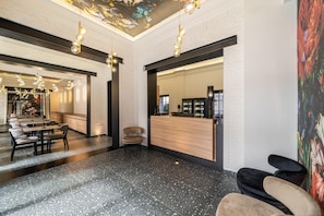 A hotel lobby with a reception desk, seating area, and a decorative ceiling.