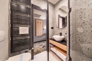 A modern bathroom with a freestanding toilet, a sink with a mirror above it, and a towel rack.