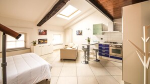 A compact apartment with a kitchenette, a dining area, and a bed.