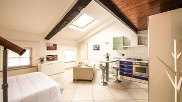 Un appartement compact comprenant un coin cuisine, un espace repas et un lit.