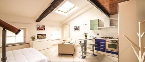 A compact apartment with a kitchenette, a dining area, and a bed.