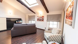 A modern living space with a sofa, patterned armchairs, a television, and artwork on the walls.