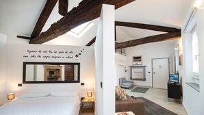 A hotel room with a bed, a mirror, a fireplace, and a television.