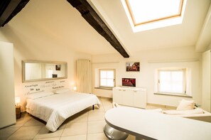 Un dormitorio con cama, tocador, televisión y tragaluz.