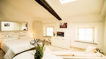 Une chambre d’hôtel avec un lit, un canapé, une télévision et une fenêtre.