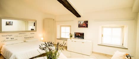 Una camera d'albergo con un letto, una poltrona, una televisione e una finestra.