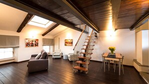 A spacious loft with a wooden staircase, a dining area, and a cozy seating area.
