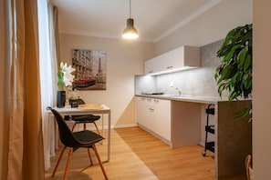A compact kitchen with a dining area, a pendant light, and a large plant. - Sting Apartments Havv Oov (Havirov)