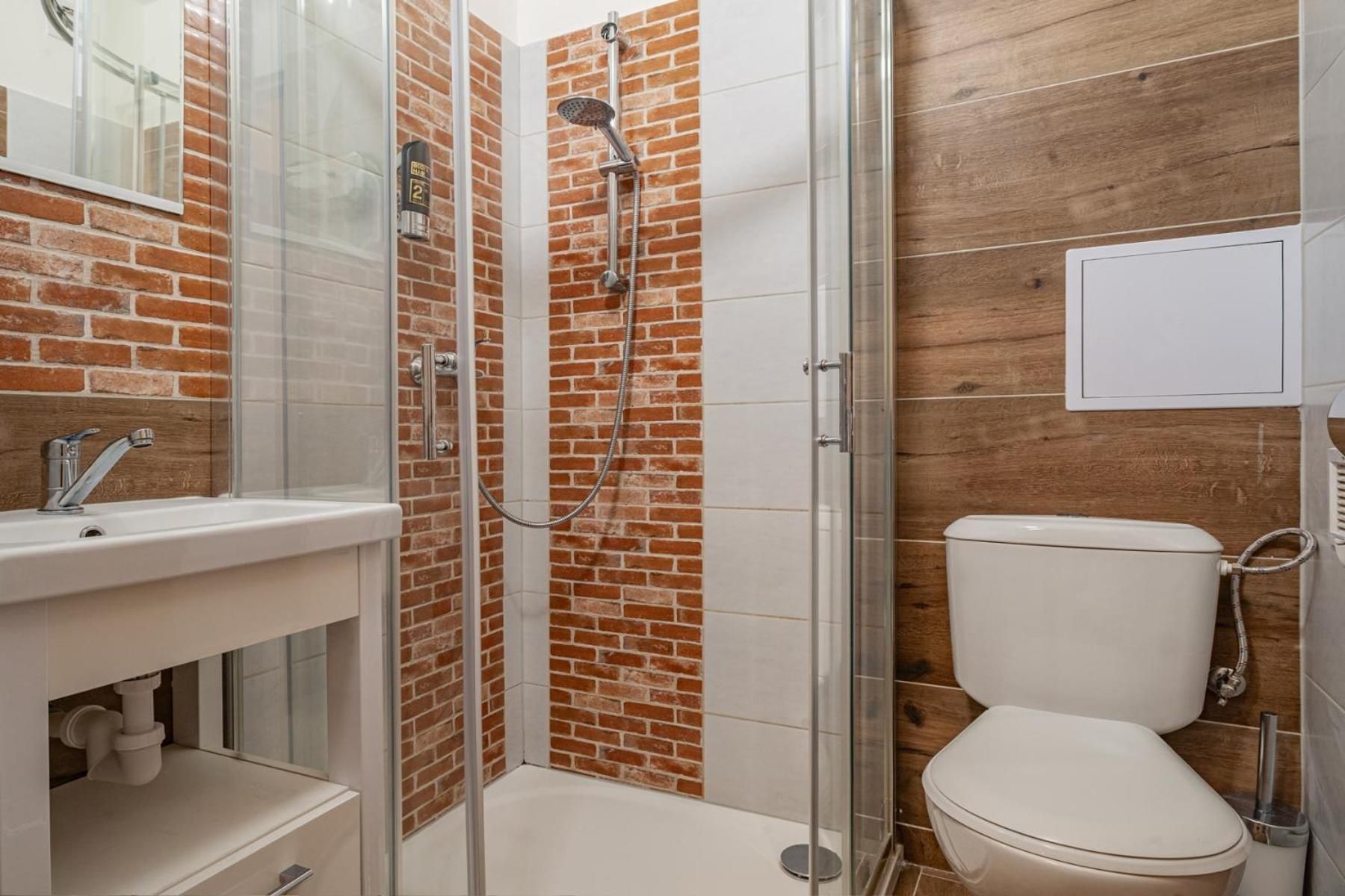 Un baño con ducha de vidrio, lavamanos blanco y un inodoro.