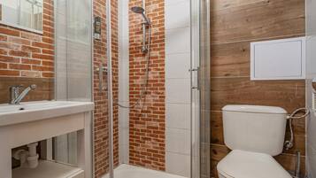 Un baño con ducha de vidrio, lavamanos blanco y un inodoro.
