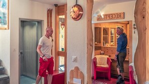 Un vestíbulo de hotel con un mostrador de recepción de madera, una silla roja y un cartel que dice 'RECEPTION'.