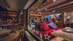 A cozy interior with a seating area, wooden beams, and a reception desk. - Hotel Mirabeau (Bagnes)