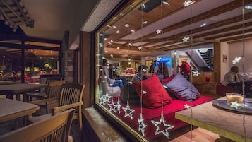 Interior acolhedor com área de estar, vigas de madeira e balcão de recepção.