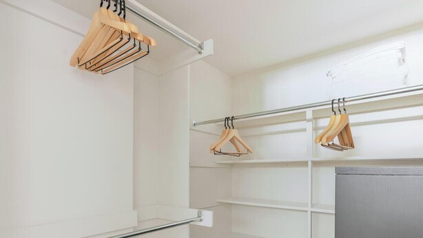A white interior with a metal rod rack holding wooden hangers. - Blueground | Ballston, pool, nr Arlington Park (Arlington)