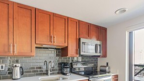 A modern kitchen with wooden cabinets, a microwave, a stove, and a coffee maker. - Blueground | Ballston, pool, nr Arlington Park (Arlington)