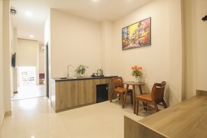 A modern kitchen with a wooden countertop, a sink, and a potted plant. There is a dining area with a wooden table and chairs, and a painting on the wall. - DE LUSTORA II (CAU ONG LANH WARD)