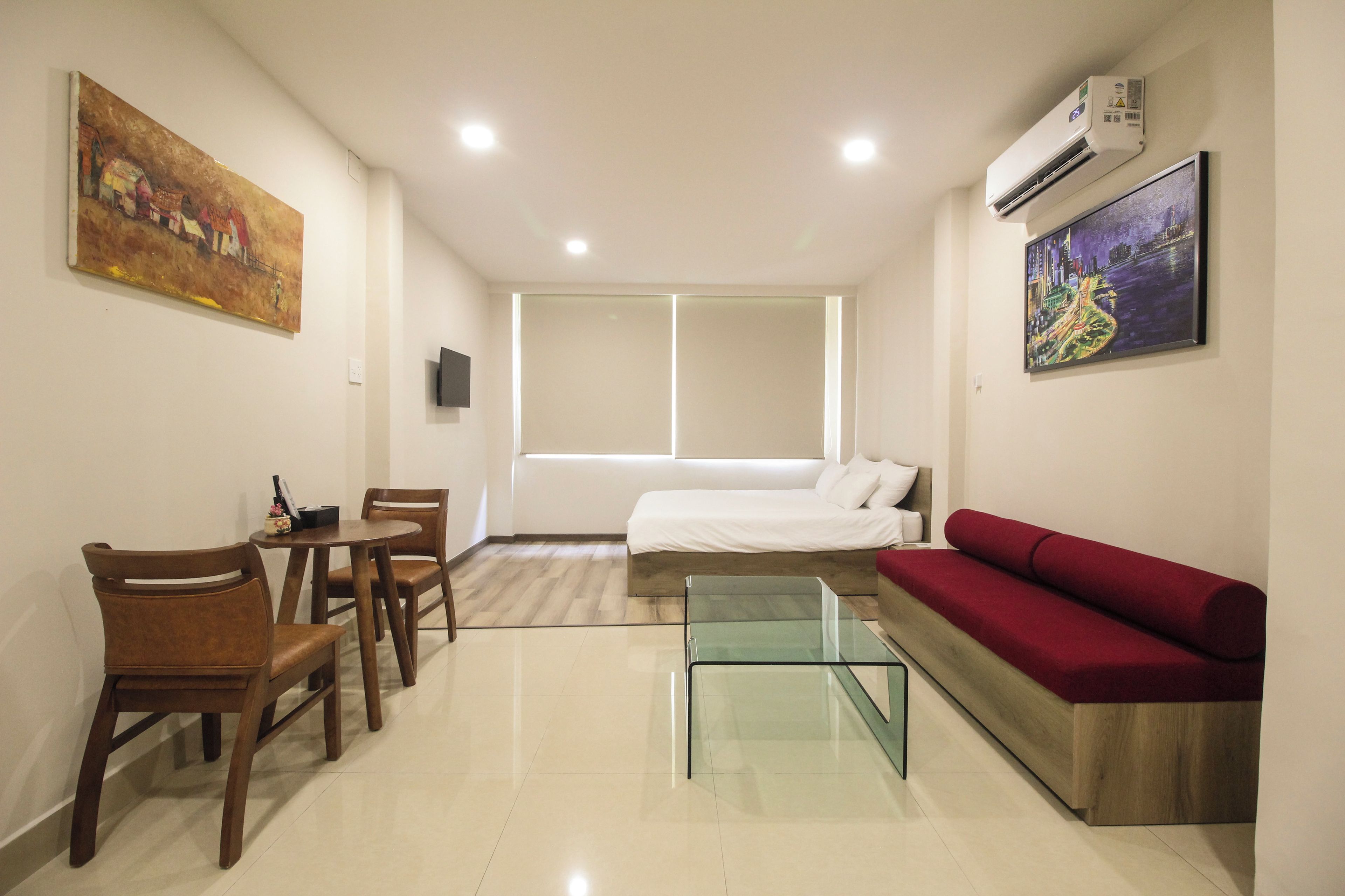 A modern living room with a glass coffee table, a red sofa, a bed, and a dining area with chairs.