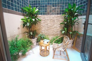 A small, enclosed patio area with potted plants, a wicker chair, and a small table. - DE LUSTORA II (CAU ONG LANH WARD)