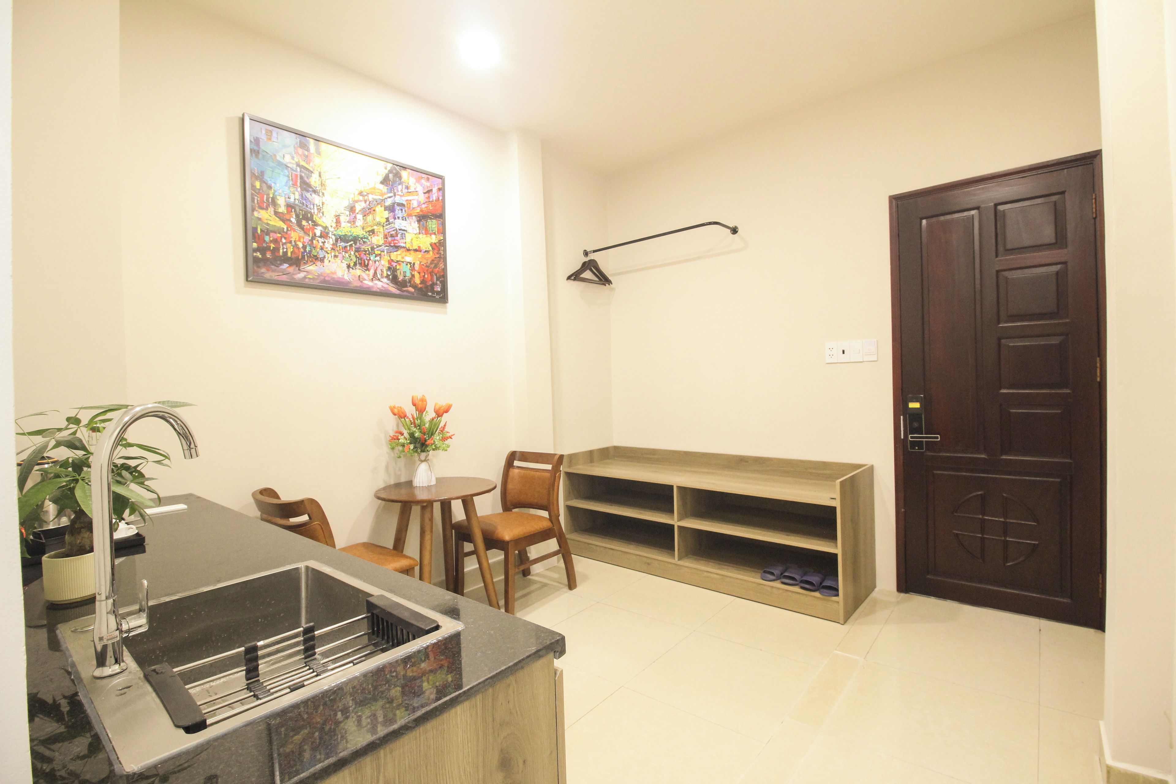A compact living space with a kitchen area, a dining table, a seating arrangement, and a door.